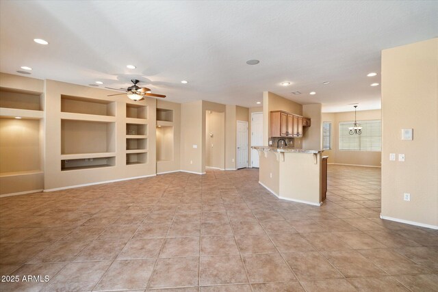 kitchen with built in shelves, baseboards, a kitchen bar, recessed lighting, and ceiling fan with notable chandelier