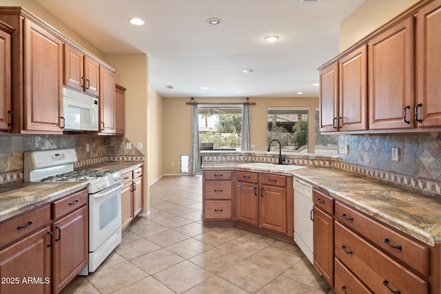 kitchen with recessed lighting, white appliances, brown cabinets, and a sink