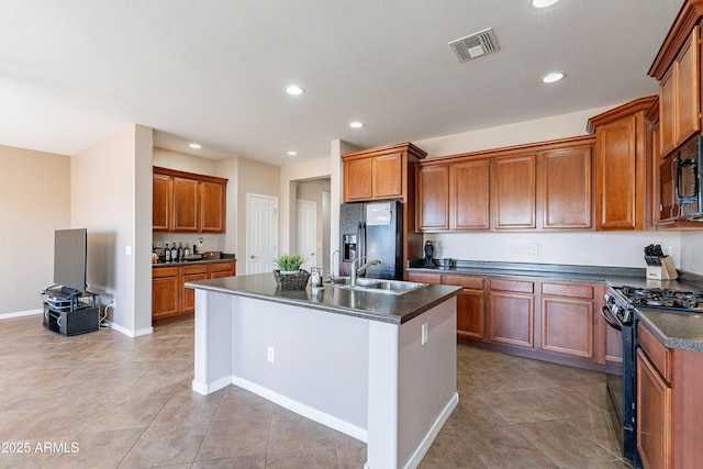 kitchen featuring sink, light tile patterned flooring, black appliances, and a center island with sink