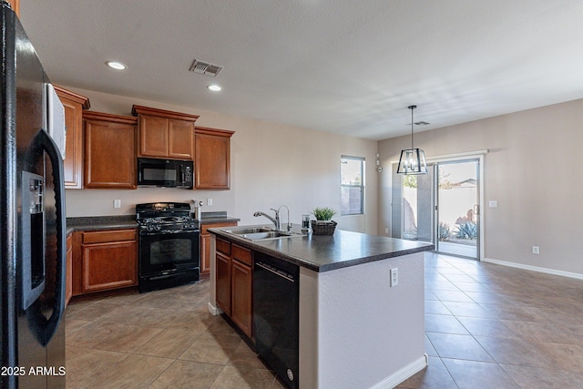 kitchen featuring light tile patterned flooring, sink, decorative light fixtures, a center island with sink, and black appliances