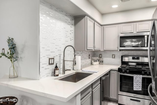 kitchen with backsplash, gray cabinetry, appliances with stainless steel finishes, and a sink