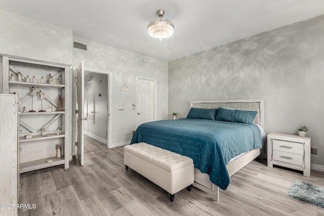 bedroom featuring baseboards, wood finished floors, and visible vents