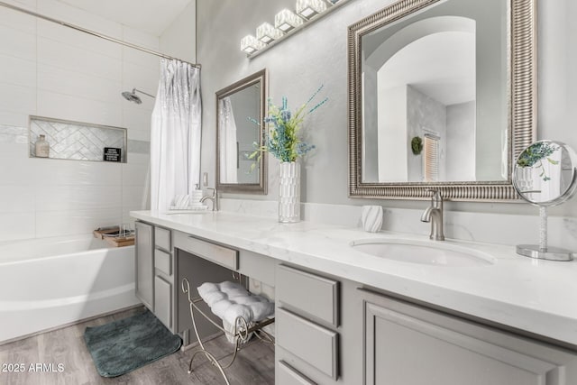 bathroom featuring double vanity, a sink, wood finished floors, and shower / bath combo