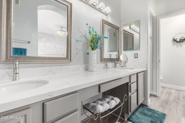 full bath with double vanity, visible vents, a sink, and wood finished floors
