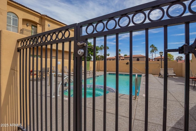 view of pool featuring fence, a gate, a pool with connected hot tub, and a patio area