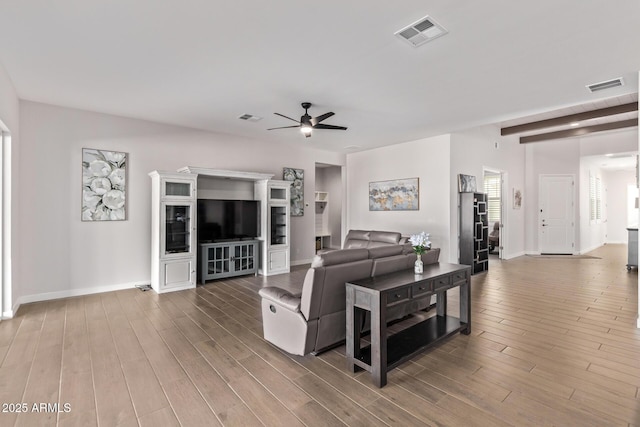 living area with a ceiling fan, visible vents, and wood finished floors