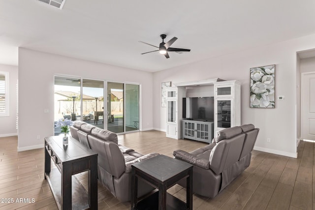 living area featuring a ceiling fan, visible vents, baseboards, and wood finished floors