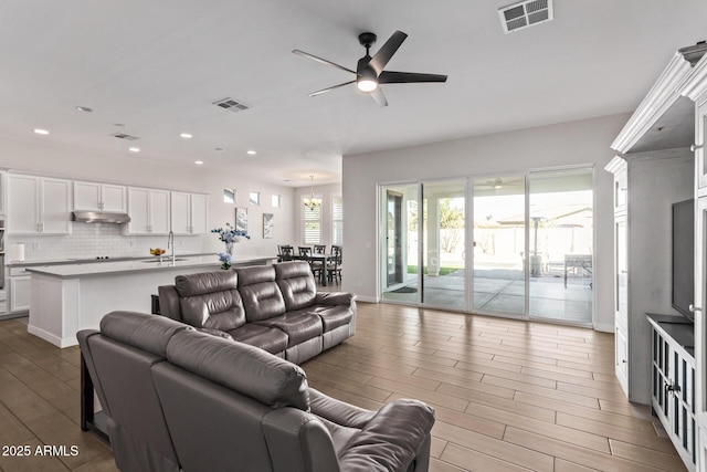 living room with ceiling fan, visible vents, wood finished floors, and recessed lighting