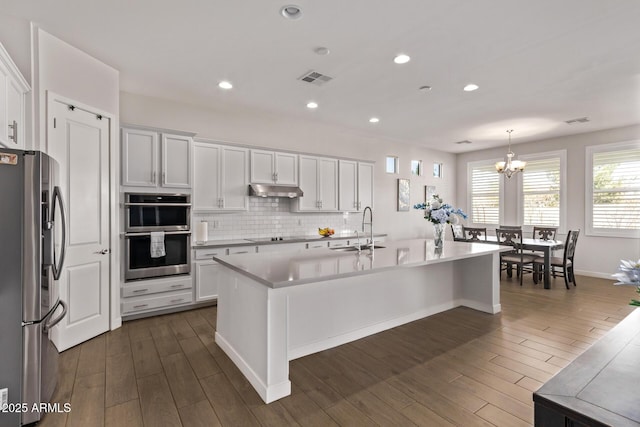 kitchen with stainless steel appliances, white cabinetry, a sink, and under cabinet range hood