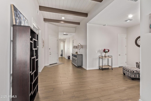 foyer entrance featuring visible vents, beamed ceiling, baseboards, and wood finished floors