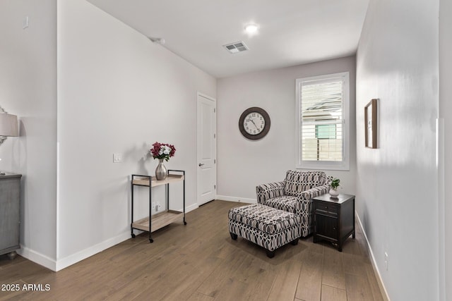 living area featuring wood finished floors, visible vents, and baseboards