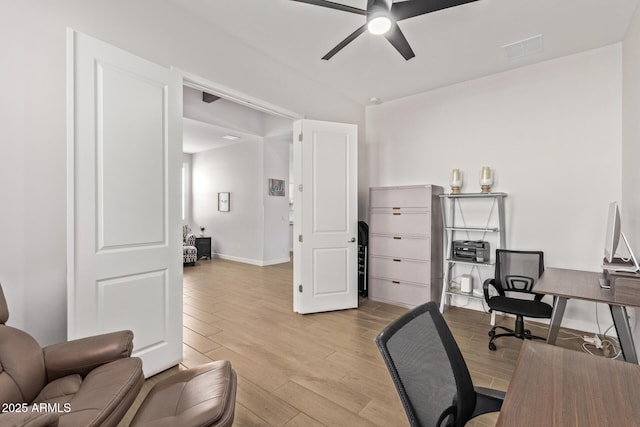 office featuring visible vents, light wood finished floors, a ceiling fan, and baseboards