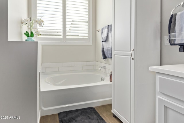 full bathroom with wood finished floors, a garden tub, and vanity