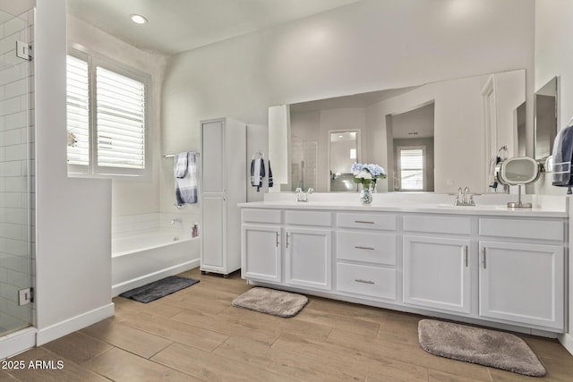 full bathroom featuring a stall shower, plenty of natural light, a sink, and wood finished floors