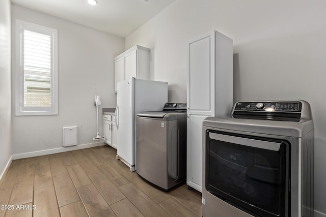 laundry area with cabinet space, washing machine and dryer, light wood-style flooring, and baseboards