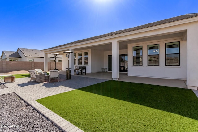 rear view of house with stucco siding, fence, outdoor lounge area, and a patio