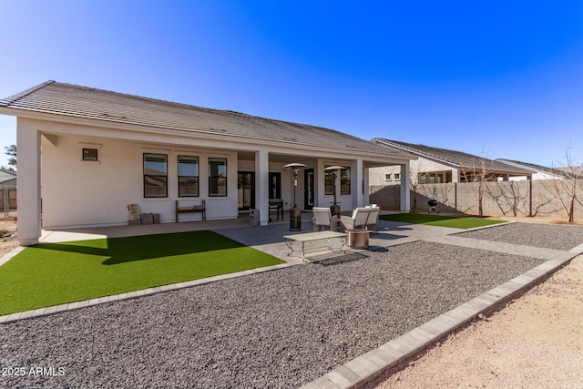 rear view of property featuring fence, a patio, and stucco siding