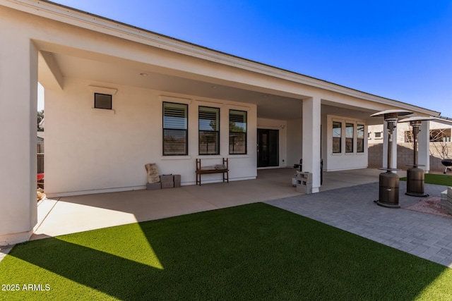 rear view of property with stucco siding and a patio