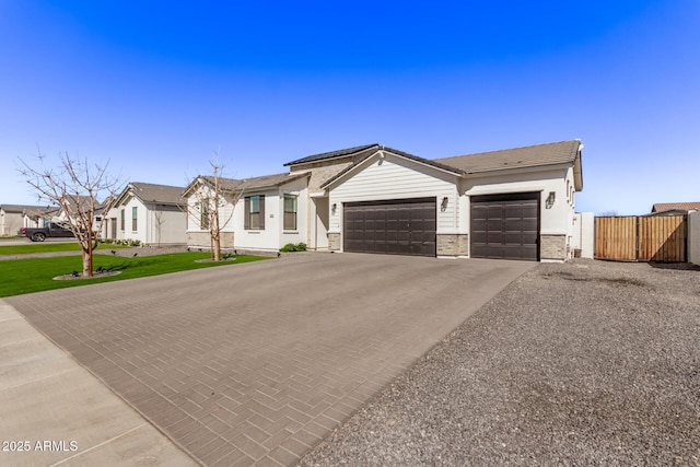 view of front of house featuring decorative driveway, brick siding, fence, a garage, and a residential view