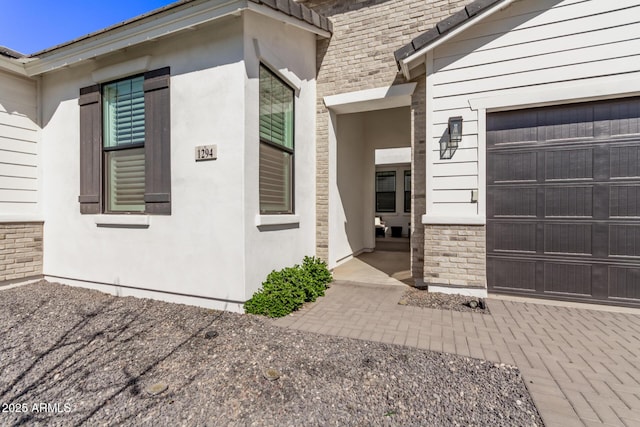 property entrance with a garage and brick siding