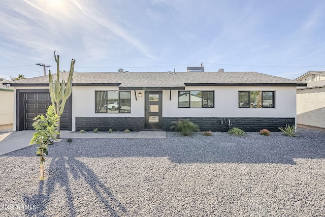 view of front of property with stucco siding, a shingled roof, concrete driveway, an attached garage, and stone siding