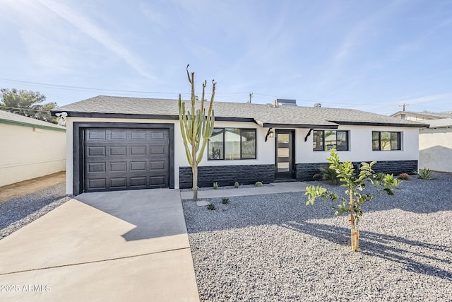 ranch-style house featuring stucco siding, a shingled roof, concrete driveway, a garage, and stone siding