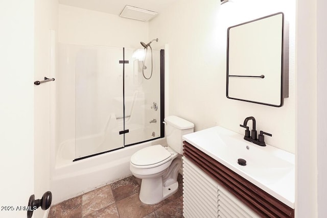 bathroom featuring vanity, toilet, stone tile flooring, and shower / bath combination with glass door