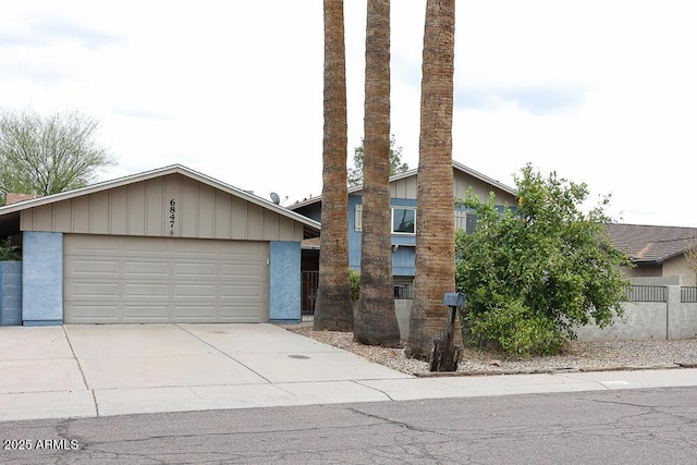 view of front of home with stucco siding, concrete driveway, an attached garage, and fence