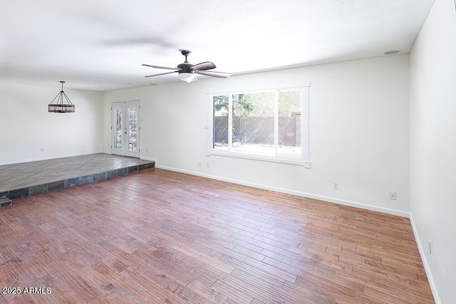 interior space featuring wood finished floors, baseboards, and ceiling fan