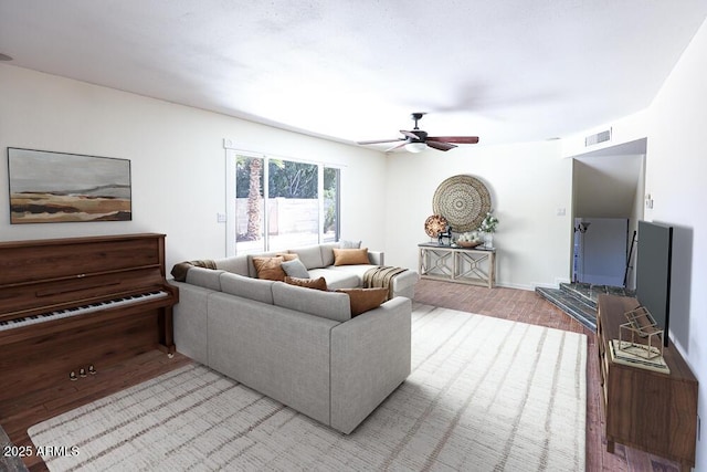 living room featuring visible vents, baseboards, wood finished floors, and a ceiling fan