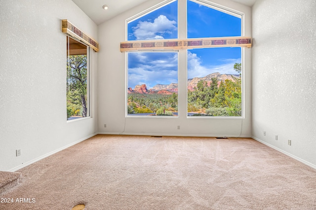 spare room with light carpet, a mountain view, and vaulted ceiling