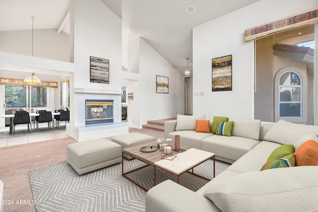 living room with light carpet, beam ceiling, high vaulted ceiling, and a tile fireplace