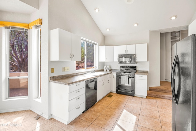 kitchen featuring lofted ceiling, black appliances, white cabinets, sink, and light tile patterned flooring