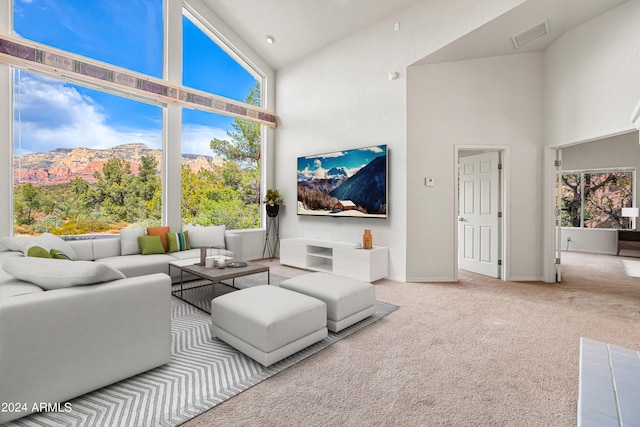 carpeted living room with high vaulted ceiling