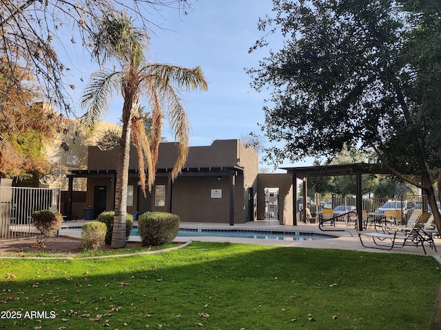 rear view of house featuring a community pool, a pergola, and a lawn