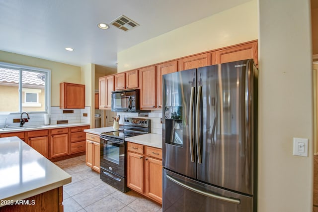 kitchen with black appliances, light countertops, a sink, and visible vents