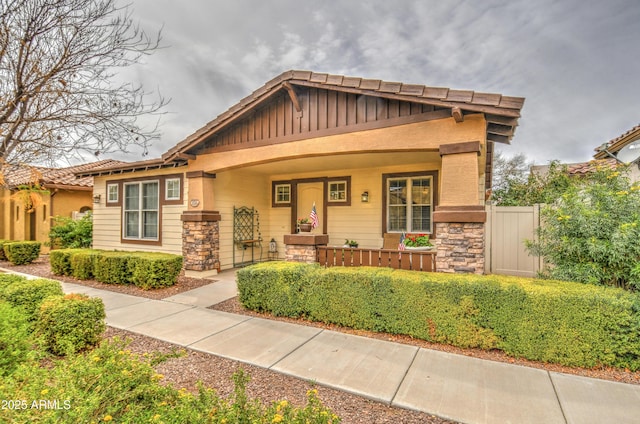 craftsman-style house featuring stone siding and covered porch