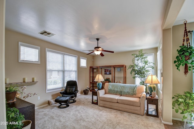 carpeted living area with ceiling fan, a wealth of natural light, visible vents, and baseboards