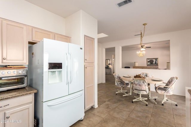 kitchen featuring white refrigerator with ice dispenser, light brown cabinetry, ceiling fan, and dark stone counters