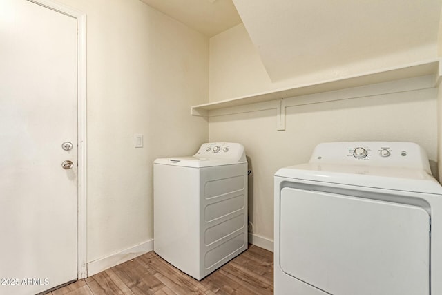 washroom featuring laundry area, washing machine and dryer, light wood-style flooring, and baseboards