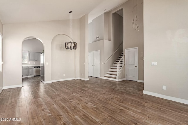 unfurnished living room featuring a chandelier, dark wood finished floors, visible vents, and baseboards