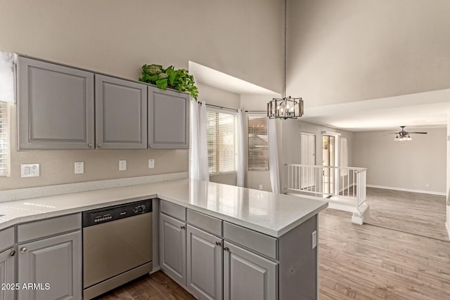 kitchen featuring dishwasher, a peninsula, gray cabinets, and decorative light fixtures