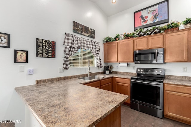 kitchen featuring dark tile patterned flooring, a peninsula, stainless steel appliances, a sink, and recessed lighting