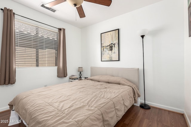 bedroom featuring a ceiling fan, baseboards, visible vents, and wood finished floors