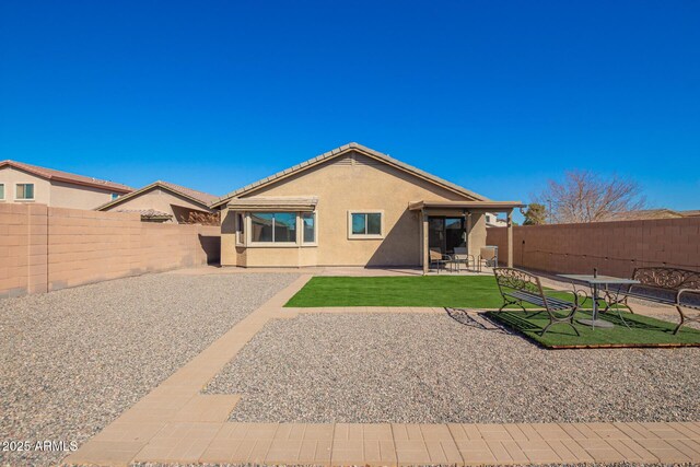 rear view of house with a patio area, a fenced backyard, a lawn, and stucco siding