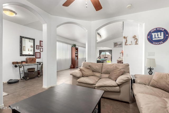 living room featuring lofted ceiling, dark tile patterned flooring, and ceiling fan