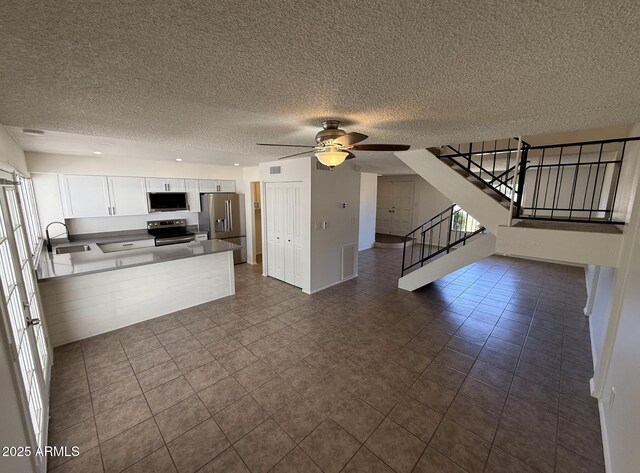 4849 W Northern Ave, Glendale, AZ 85301 - kitchen featuring appliances with stainless steel finishes, open floor plan, a peninsula, white cabinets, and a textured ceiling