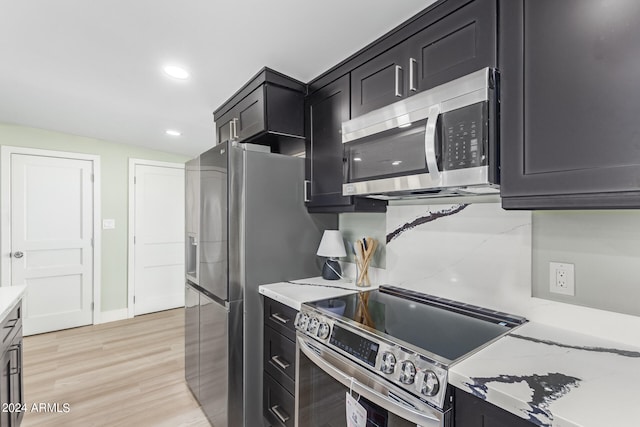 kitchen featuring light hardwood / wood-style flooring, light stone countertops, appliances with stainless steel finishes, and tasteful backsplash