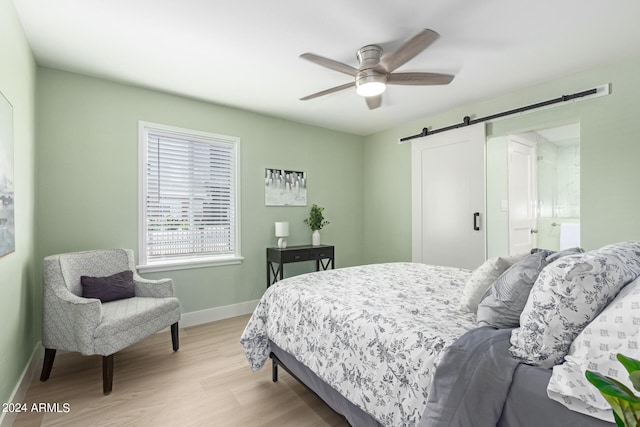 bedroom with a barn door, ceiling fan, and light wood-type flooring