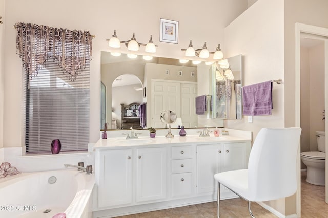 bathroom featuring tile patterned flooring, vanity, a washtub, and toilet